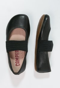 Bailarinas de cuero negro con una superficie texturizada, tira elástica, interior rosa claro y una suela flexible marrón.
