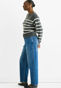 Gray and white striped sweater with a round neckline, paired with high-waisted blue jeans featuring a relaxed fit and slouchy silhouette.