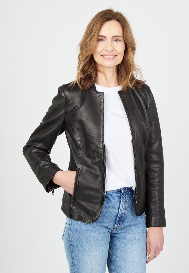 Zwarte leren jas met een zachte textuur, ritszakken en een ronde halslijn, gecombineerd met blauwe jeans en een wit T-shirt.