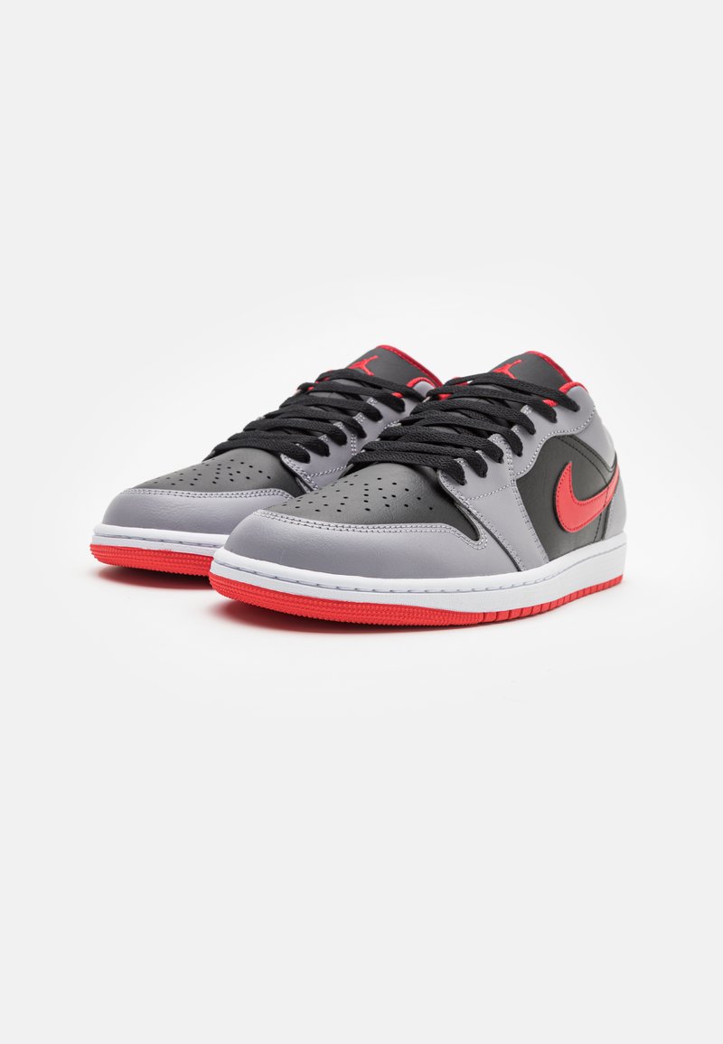 Sneakers Nike Air Jordan, z szarym skórzanym wierzchem, czarnymi akcentami, czerwonym logo Swoosh i gumową podeszwą o fakturowanym wzorze.