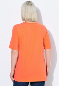 Camiseta de manga corta naranja, hecha de una tela suave, con un cuello redondo y un corte relajado, con un dobladillo curvado y sin patrones visibles.