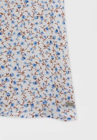 Tissu blanc avec un motif de petites fleurs bleues et tiges marron, montrant l'ourlet du bas et une petite étiquette argentée attachée.