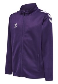 Giacca sportiva viola realizzata in tessuto liscio, con colletto alto, zip completa e accenti bianchi a forma di chevron sulle spalle. Due tasche laterali.