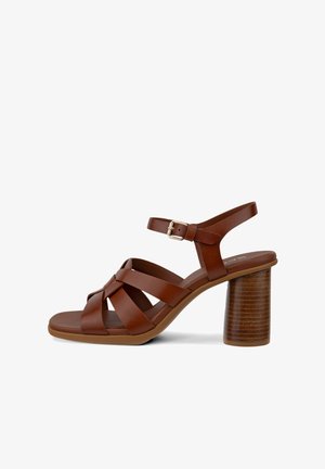 Brązowy skórzany sandał damski z krzyżującymi się paskami, regulowaną klamrą oraz grubym cylindrycznym drewnianym obcasem.