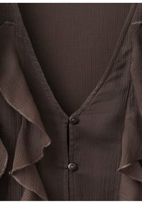 Hnědá halenka s výstřihem do V, z texturované látky a s volánkovými okraji. Na přední straně zapínaná na tmavé knoflíky.