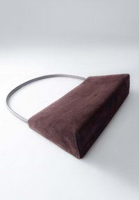 Obdélníková taška z tmavohnědé ante s tenkým, zakřiveným šedým uchem ležící na bílé ploše.