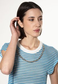 Suéter de punto de rayas azul y blanco de manga corta con un escote redondo y un detalle de cadena metálica alrededor del cuello.