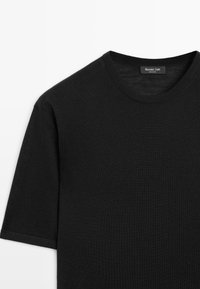 Maglione nero a maniche corte con scollo a girocollo, tessuto a maglia fine e etichetta Massimo Dutti visibile sul colletto.
