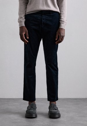 Mørke fløjl bukser med slim fit, der har flad front og subtil tekstur. Sammen med grå snørebåndssko.