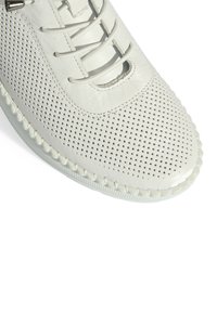Chaussure en cuir blanc avec un design perforé, fermeture à lacets, couture décorative le long de la semelle et une forme de bout arrondi.