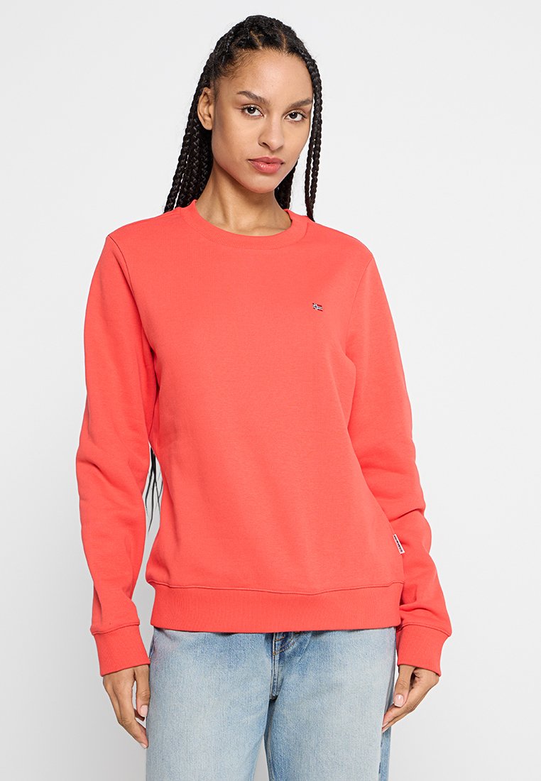 Korallefarbener Pullover aus weichem Material, mit Rundhalsausschnitt und langen Ärmeln. Kleines Logo-Detail auf der Brust und Rippbündchen.