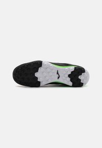 Suola di scarpa sportiva nera con gomma texturizzata e tasselli esagonali per una maggiore aderenza. Intersuola bianca con accento verde vicino al tallone.