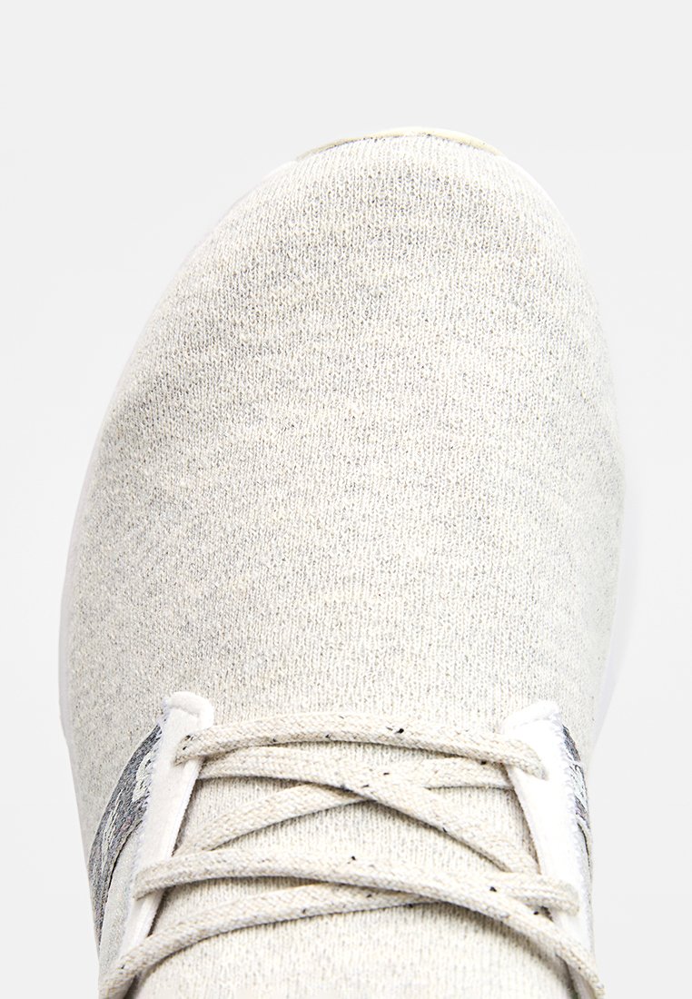 Chaussure de sport en tricot gris clair avec un bout rond, lacets blancs et une tige texturée avec un motif subtil. Semelle blanche.