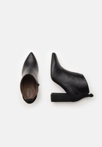 Bottines en cuir noir avec un bout pointu, un talon block texturé et un design festonné sur le col. L'intérieur présente une doublure lisse.