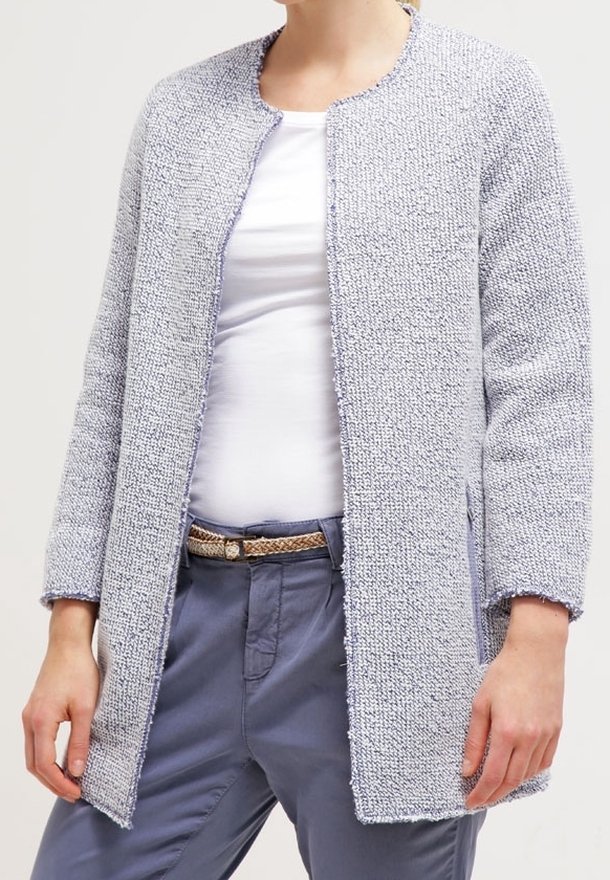 Ljusgrå texturerad cardigan med rund halsringning, öppen framsida och långa ärmar. Bärs över en vit skjorta och kombineras med blå byxor.