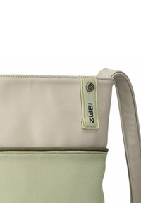 Borsa in pelle beige e verde chiaro con fondo testurizzato, tasca con cerniera e etichetta con il marchio "iam2". Tracolla regolabile.