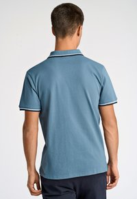 Męska koszulka polo z krótkim rękawem w jasnoniebieskim kolorze, wykonana z bawełny. Posiada prążkowany kołnierzyk z granatowymi i białymi paskami, prosty design i dopasowany krój.