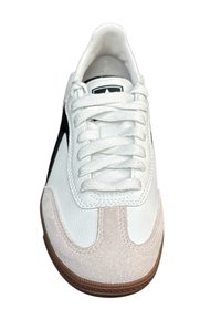 Fehér bőr felsőrészű sneakers, világos bézs velúr részletekkel, fekete kiegészítőkkel és fehér fűzőkkel. Az alja barna gumitalppal rendelkezik.