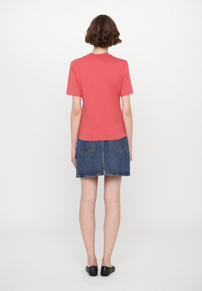 Coral short-sleeve t-shirt paired with a blue denim skirt. The skirt features back pockets and a slightly frayed hem. Black flat shoes complete the look.