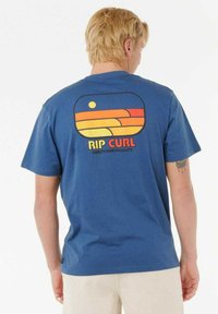 Blaues Baumwoll-T-Shirt mit kurzen Ärmeln, das auf der Rückseite eine retro Grafik zeigt, einschließlich orangefarbenen, gelben und roten Wellenmustern sowie einer Sonne.