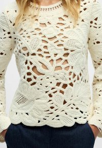 Creme hæklet sweater med blomster mønstre, lange ærmer og åben struktur, med bølgede nederste kanter og struktureret syning.