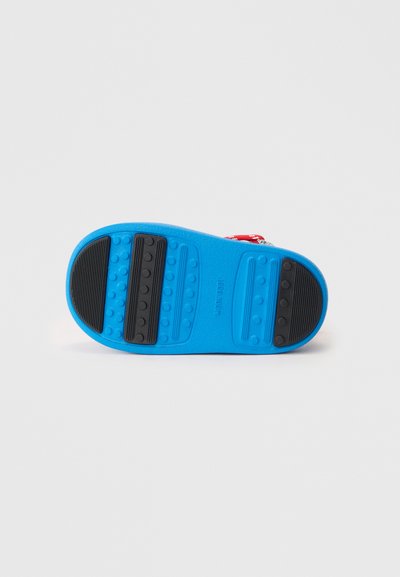 Semelle de chaussure en caoutchouc bleu avec des accents noirs texturés et des motifs d'adhérence ; présente des bosses surélevées pour la traction et la durabilité.