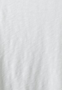 Tessuto bianco testurizzato con un fine pattern ondulato, superficie liscia e aspetto morbido. Adatto per vari capi d'abbigliamento e accessori.