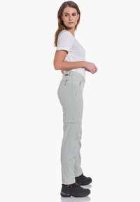 Pantalones exteriores de color gris claro con un bolsillo lateral con cremallera, piernas ajustadas y una cinturilla recta, combinados con una camiseta blanca y zapatos negros.