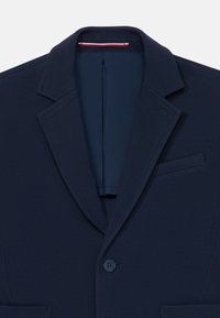 Námornícky modrý blejzer z textúrovaného materiálu, s klopovým golierom, zapínaním na jeden gombík a dizajnom vrecka na hrudi.