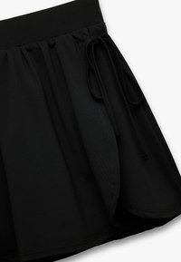 Falda negra de cintura elástica con diseño fruncido y cierre con cordón. Textura suave con una silueta fluida y detalles de costura limpios.