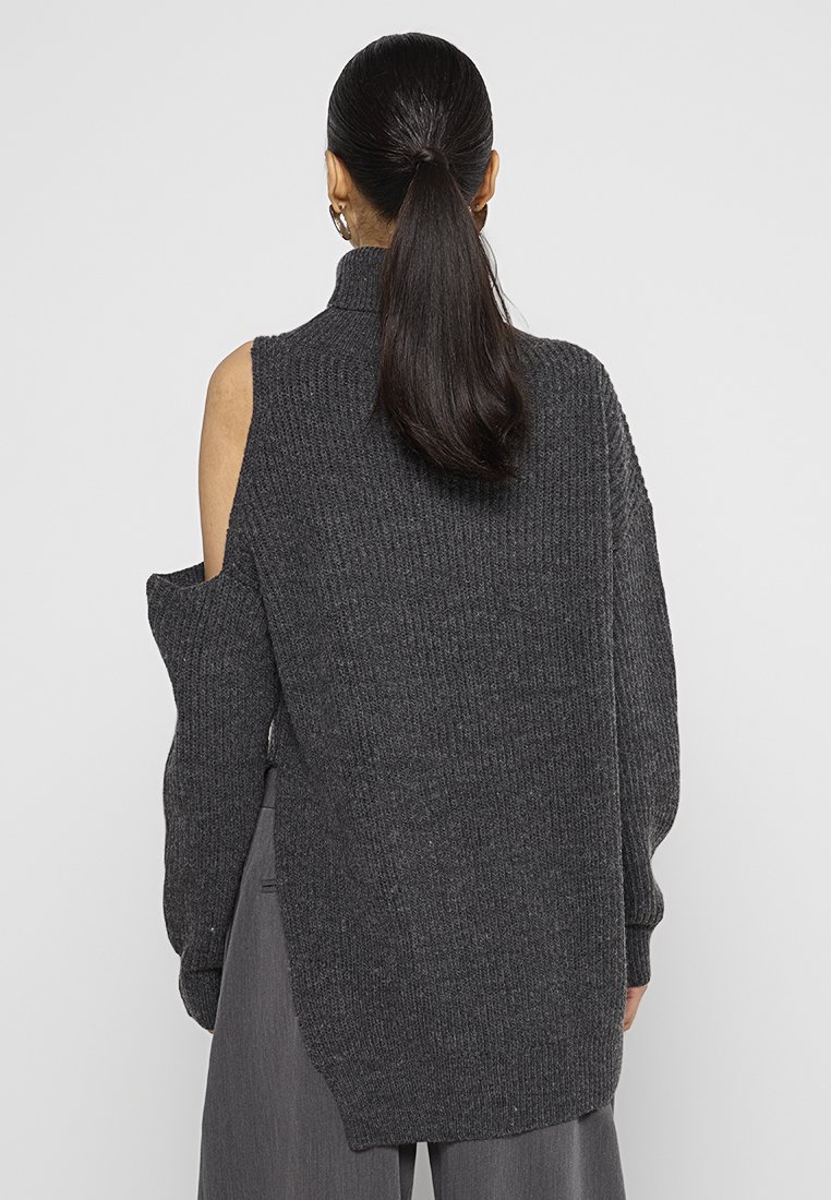 Maglione oversize grigio scuro a maglia con collo alto e design con spalle scoperte, caratterizzato da una texture a coste e un orlo posteriore più lungo.