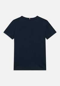 Tamsiai mėlynas trumpomis rankovėmis marškinėliai su apvaliu kaklu, kurių gale yra mažas vertikalias raudonas, baltas ir mėlynas dryželis.