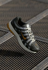 Nike running shoe with a gray mesh upper, white and orange accents, padded collar, gray laces, and a textured rubber sole.