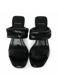 Sandales noires avec une large bride tressée et un semelle lisse. Conception à bout carré avec une finition brillante. Nom de la marque "MIRIADA" visible.