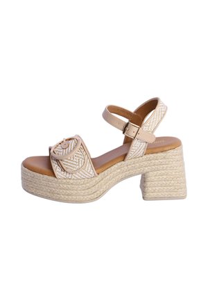 Sandalia de plataforma beige con textura tejida, tacón bloque, correa en el tobillo con hebilla y correa frontal con detalle de hebilla circular.