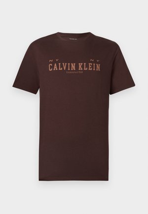 Tmavohnedé bavlnené tričko s logom „CALVIN KLEIN“ v svetlejšej hnedej farbe. Krátke rukávy, okrúhly výstrih a rovný spodný lem. Jednoduchý dizajn.