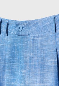 Pantaloni di lino azzurro chiaro con un tessuto texturizzato e una finitura liscia, chiusura con bottone singolo e pieghe ripiegate in vita.
