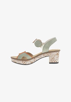 Sandales vertes et beiges avec un talon épais, présentant des détails décoratifs orange et une semelle extérieure à motifs blancs et marron.