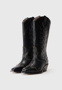 Stivali da cowboy in pelle nera con cuciture intricate e accenti di borchie, punta affusolata e tacco impilato moderato. Pattern decorativi dettagliati.