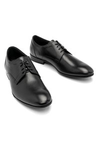 Czarne skórzane buty na formalne okazje z gładkim wykończeniem, spiczastym noskiem, wiązanym designem i minimalistycznym przeszyciem. Niski obcas z wypolerowaną powierzchnią.