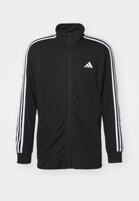 Crna zip-up jakna za trčanje napravljena od glatke tkanine, s bijelim bočnim prugama i malim bijelim logotipom na prsima.