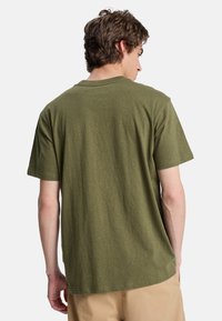Olive green t-shirt made of soft fabric, featuring a classic crew neckline and short sleeves, with a textured, slightly speckled pattern.