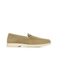 Zapato de ante marrón claro tipo slip-on con punta redondeada, suela crema y un pequeño acento de botón negro cerca del empeine. Superficie texturizada.