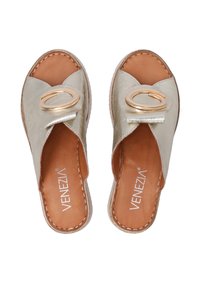 Metallisch goldene Slipper-Sandalen mit einer abgerundeten Spitze, ausgestattet mit einem dekorativen Riemen und einem kreisförmigen Akzent, auf einer hellbraunen Lederinnensohle.
