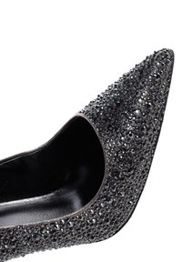Scarpa nera con tacco alto e punta affusolata, decorata con scintillanti strass neri e argentati, con una fodera interna liscia.
