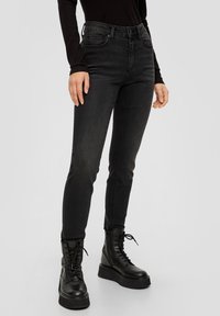 Svarta smala jeans med hög midja och fem fickor. En slät denimtextur, tillsammans med svarta snörstövlar som går upp till anklarna.