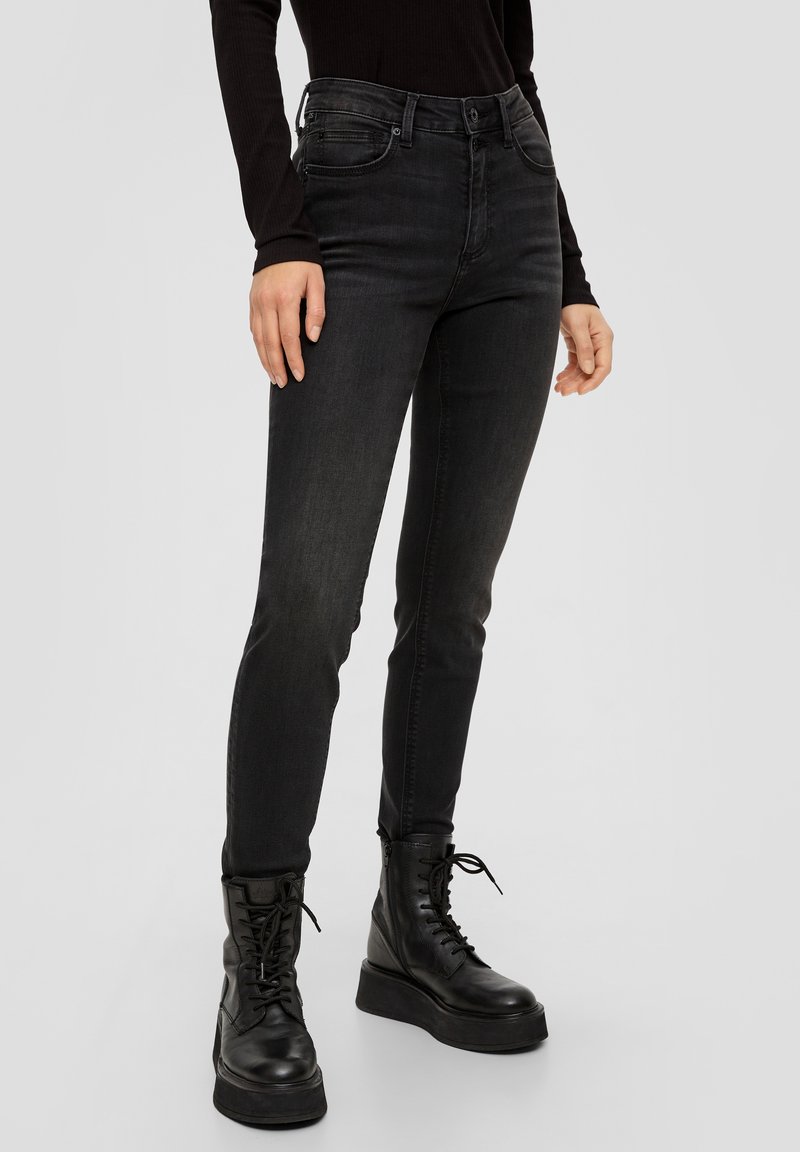 Svarta smala jeans med hög midja och fem fickor. En slät denimtextur, tillsammans med svarta snörstövlar som går upp till anklarna.