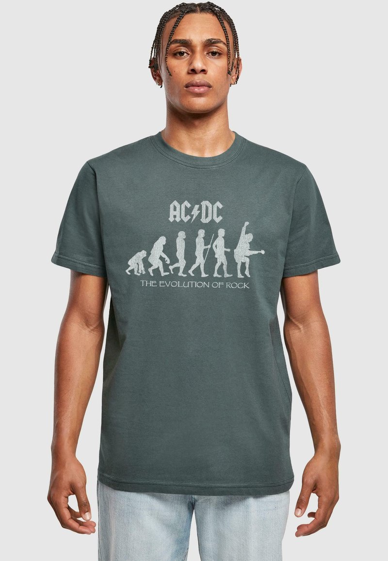 Mørkegrøn bomulds t-shirt med hvidt AC/DC grafik kunstværk, der skildrer udviklingen af rockdesign. Korte ærmer, rund halsudskæring, afslappet pasform.