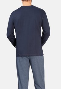 Marineblaues langärmeliges T-Shirt aus Baumwolle mit Rundhalsausschnitt und geradem Saum, kombiniert mit gemusterten blauen Pyjamahosen.