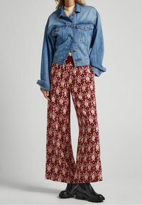 Denimjacka med boxig passform och knappstängning, kombinerad med vida, burgundy mönstrade byxor med elfenbensfärgade geometriska mönster. Svarta stövlar.